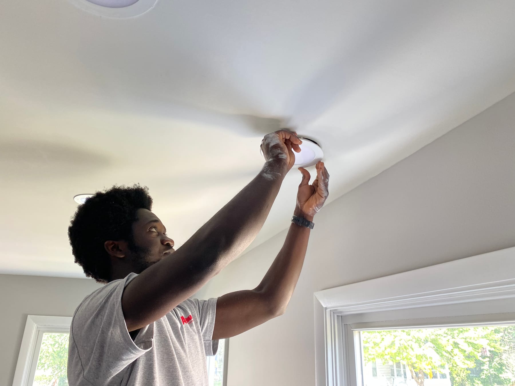 A Fine Line electrician installing a ceiling fixture in a Kent County home
