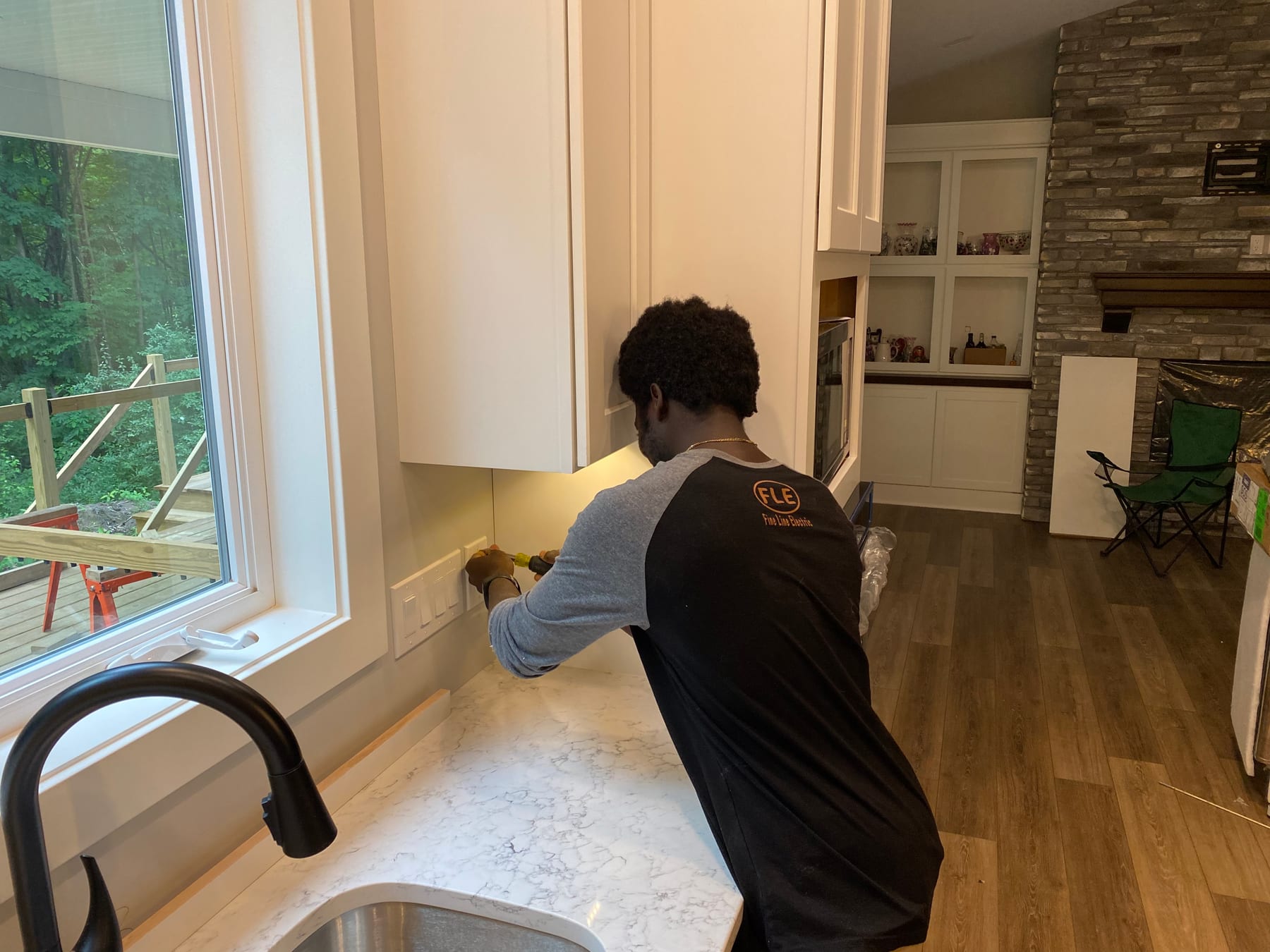 A Fine Line electrician finishing under-cabinet lighting at a kitchen counter